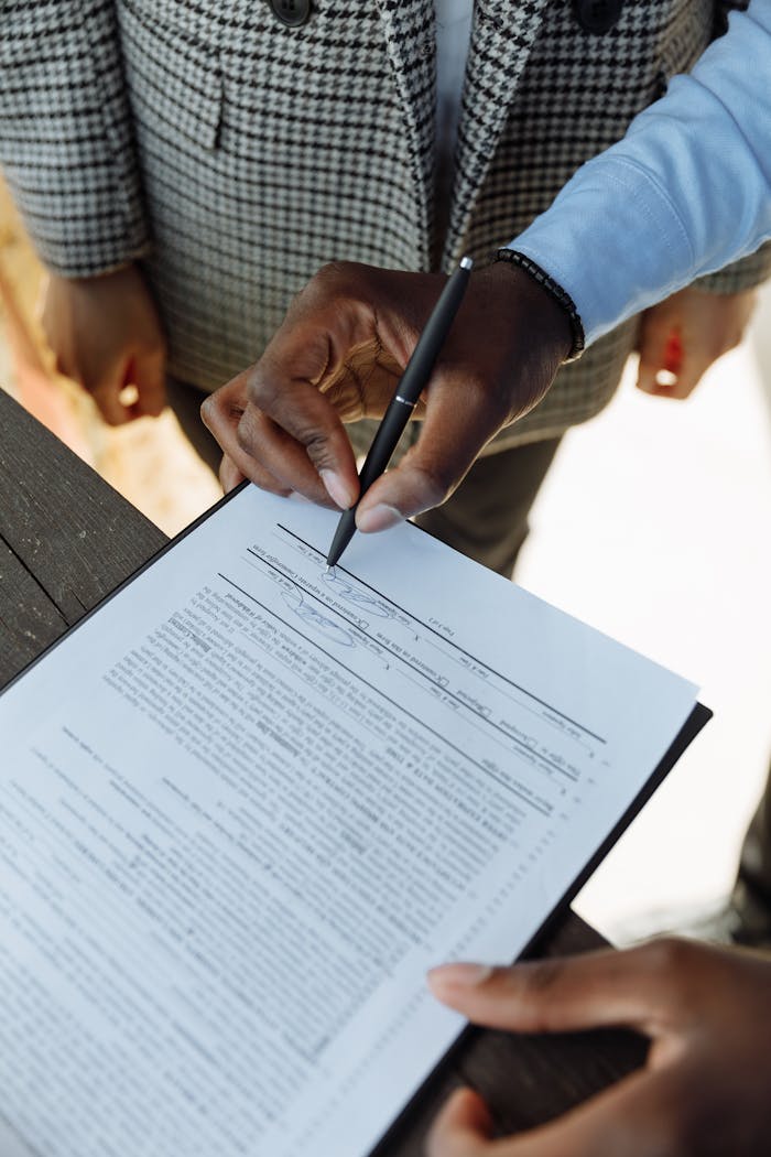 Detailed view of a person signing a business contract with a pen, emphasizing agreement and ownership.
