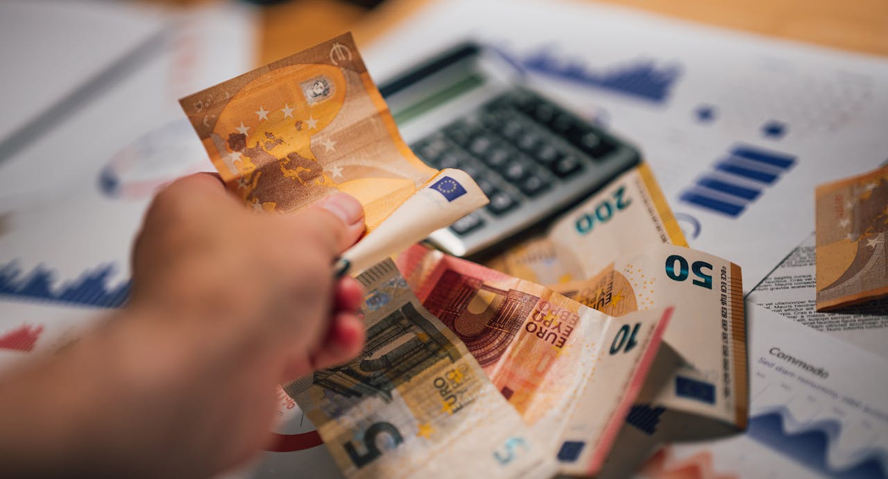 Close-up of Euro banknotes on financial documents and a calculator, depicting financial planning.